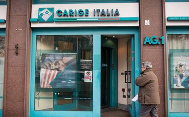 A man walks near a Banca Carige Italy. Banca Carige is an